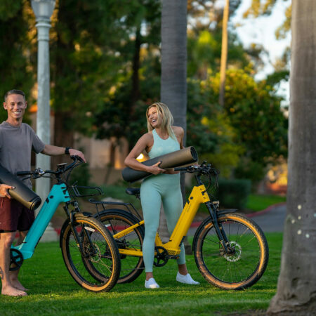 Zwei Personen mit E-Bikes und Yoga-Matten genießen eine entspannte Zeit im Park.