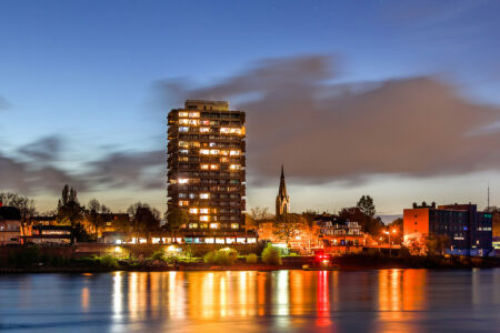 Nachtaufnahme des Hotel Rheingarten in Duisburg, mit beleuchtetem Gebäude und reflektierenden Lichtern im Rhein.